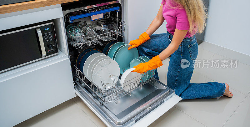 Young woman takes dishes out of the dishwasher machine
